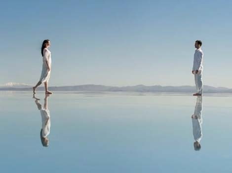 Une femme et un homme ainsi que leur reflet dans l'eau